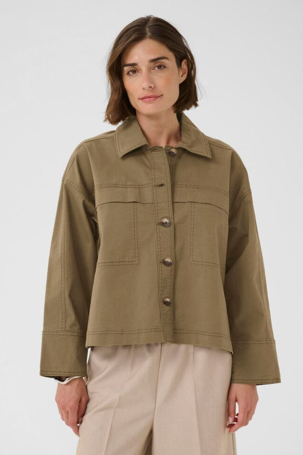 Woman wearing an olive green jacket with button details on a white background